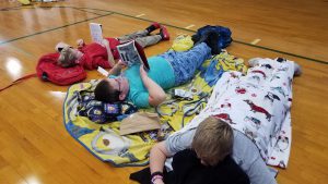 photo shows children laying on gymnasium floor reading books