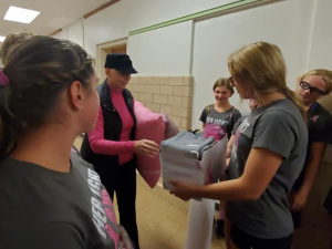 photo shows girl holding box giving it to adult