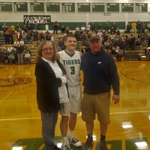 HFHS basketball player Riley Maddison poses for a picture, flanked by his parents, after scoring his 1,000 career point.