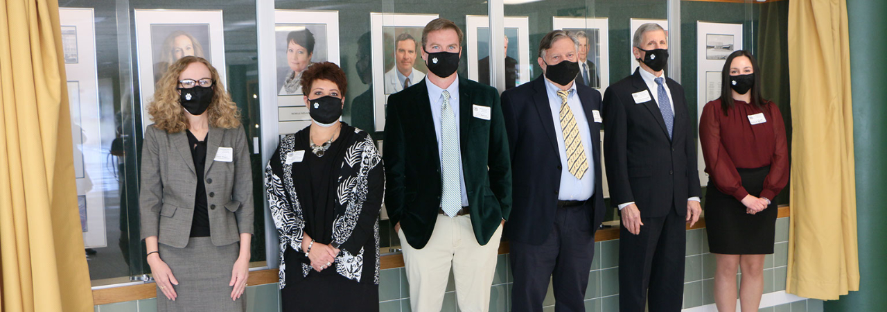 photo shows group of adults in front of wall masked