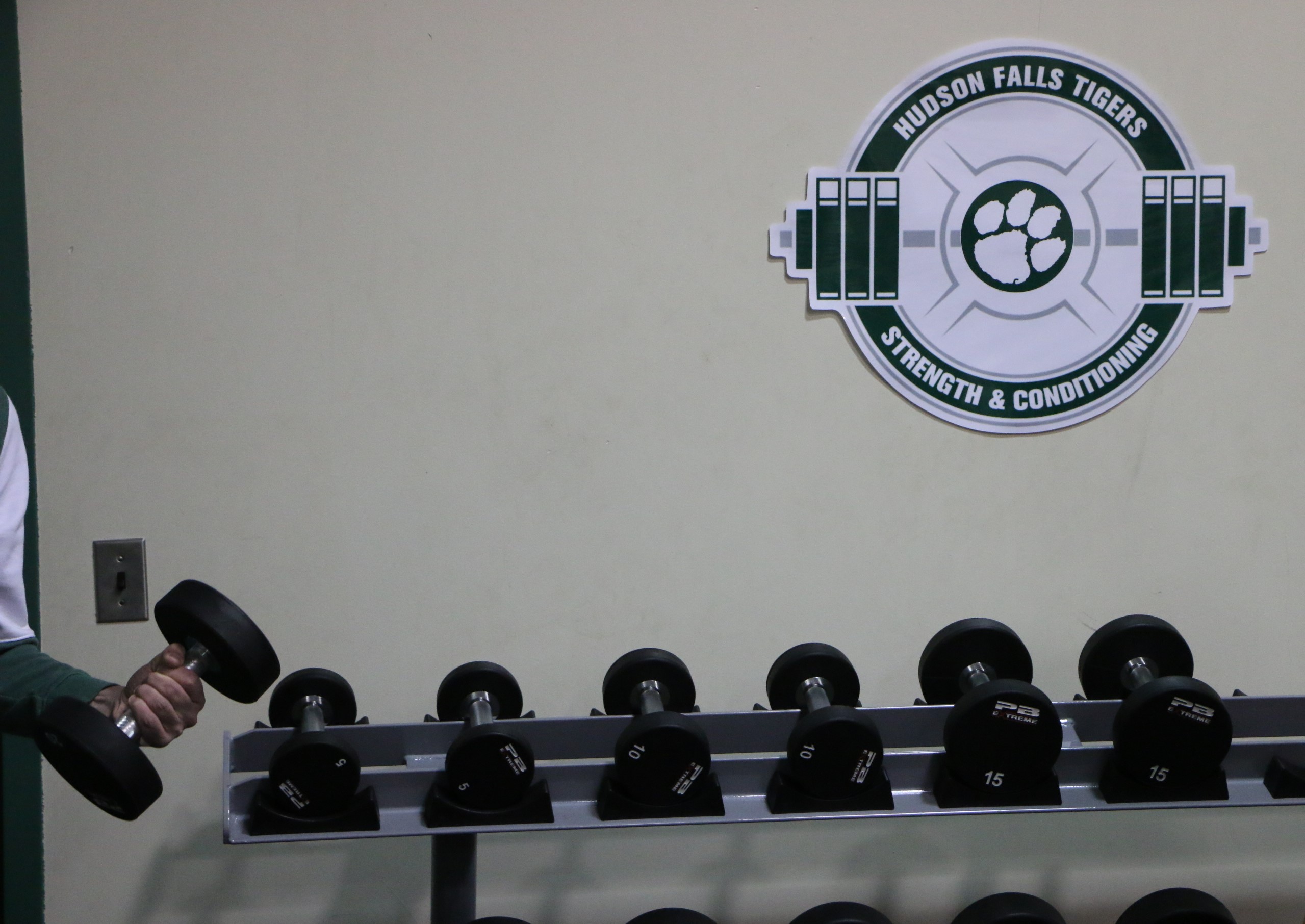 Rack of dumbells with Hudson Falls strength and conditioning logo