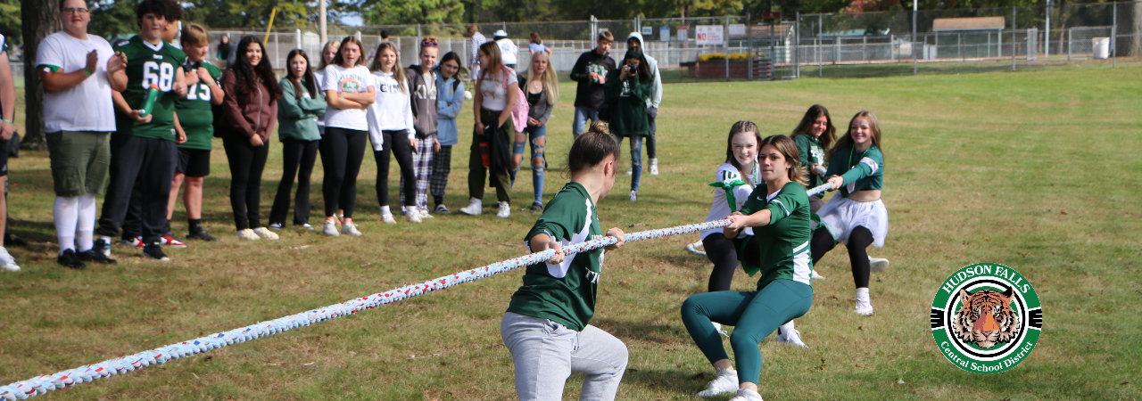 Photo of girls doing tug of war with students looking on