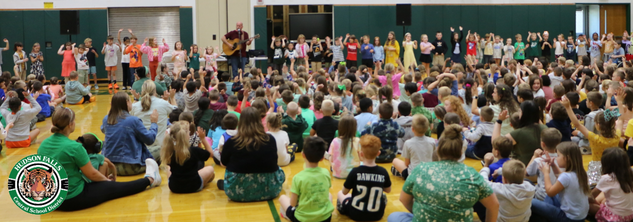 Photo of the primary school attending a welcome back concert in the gym with dancing in the front